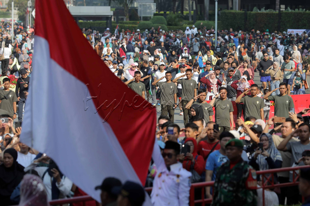 Warga berserta aparat keamanan memberikan hormat upacara bendera Hari Kebangsaan saat berlangsungnya Hari Bebas Kendaraan Bermotor (HBKB) di Depan Pos polisi Bundaran HI, Jakarta Pusat, Minggu (25/8/2024).&nbsp;