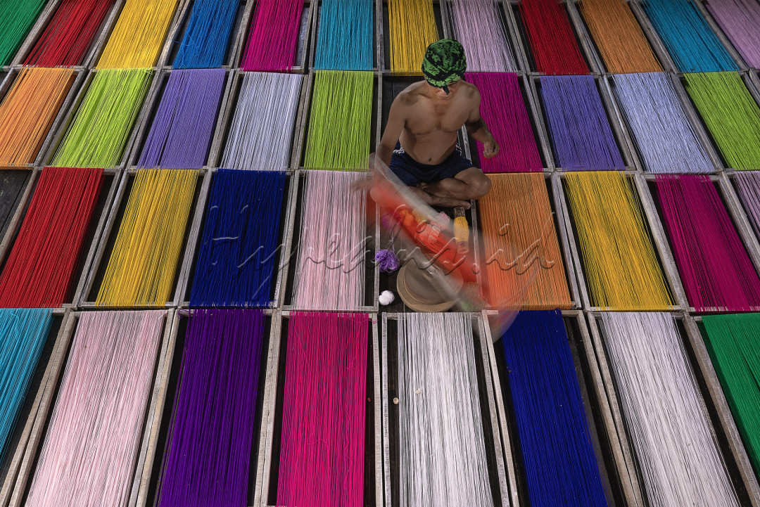 Kegiatan seorang pemintal benang yang sedang bekerja.