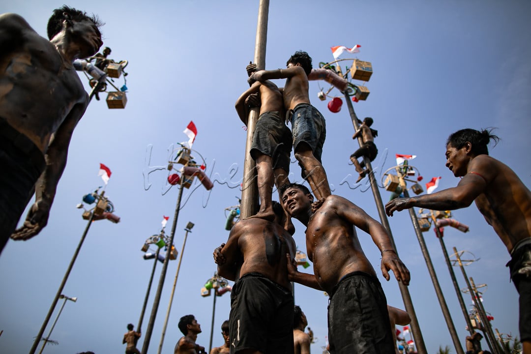 Para peserta berusaha mencapai puncak tiang yang dilumuri minyak untuk mendapatkan hadiah dalam kompetisi panjat pinang di Pantai Festival Ancol, Jakarta Utara, Sabtu (17/8/2024).&nbsp;Sebanyak 51 batang pinang dengan beragam hadiah menarik seperti peralatan rumah tangga dan sepeda itu disediakan dalam lomba yang diikuti ratusan warga&nbsp;untuk memeriahkan momen Hari Ulang Tahun (HUT) ke-79 Republik Indonesia yang jatuh pada tanggal 17 Agustus 2024.