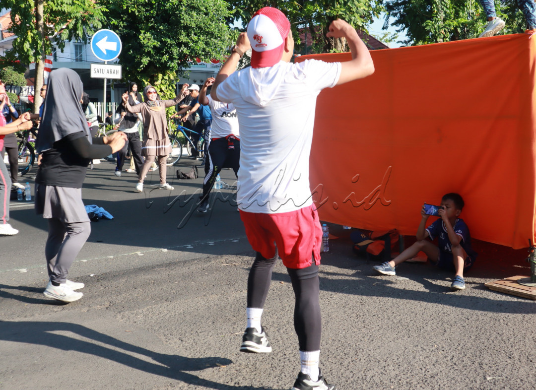 Judul: PHYSYCAL SPORT VS E-SPORT<br />
Tampak seorang anak kecil sedang melakukan aktifitas e-sport saat orang dewasa lainnya melakukan aktifitas aerobik di car free day Surabaya 24 Agustus 2024