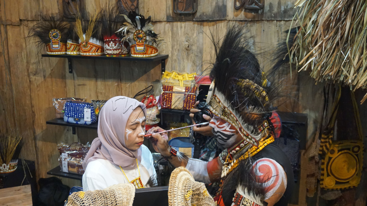 Perajin dari Papua melakukan <em>face painting&nbsp;</em>pada pengunjung di pameran Kriyanusa 2024, di Jakarta Convention Center (JCC) Jakarta, Jumat (30/8/2024). Pameran yang menjadi wadah serta platform&nbsp;promosi para perajin dari berbagai daerah di Tanah Air tersebut bertujuan melestarikan kebudayaan Nusantara.&nbsp;