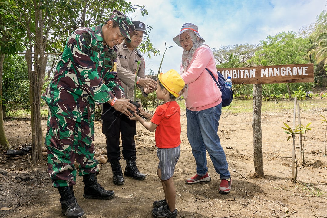Anggota TNI dan POLRI berbagi pohon bakau pada seorang ibu dan anaknya saat gelar konservasi di Pantai Bajulmati Kab. Malang