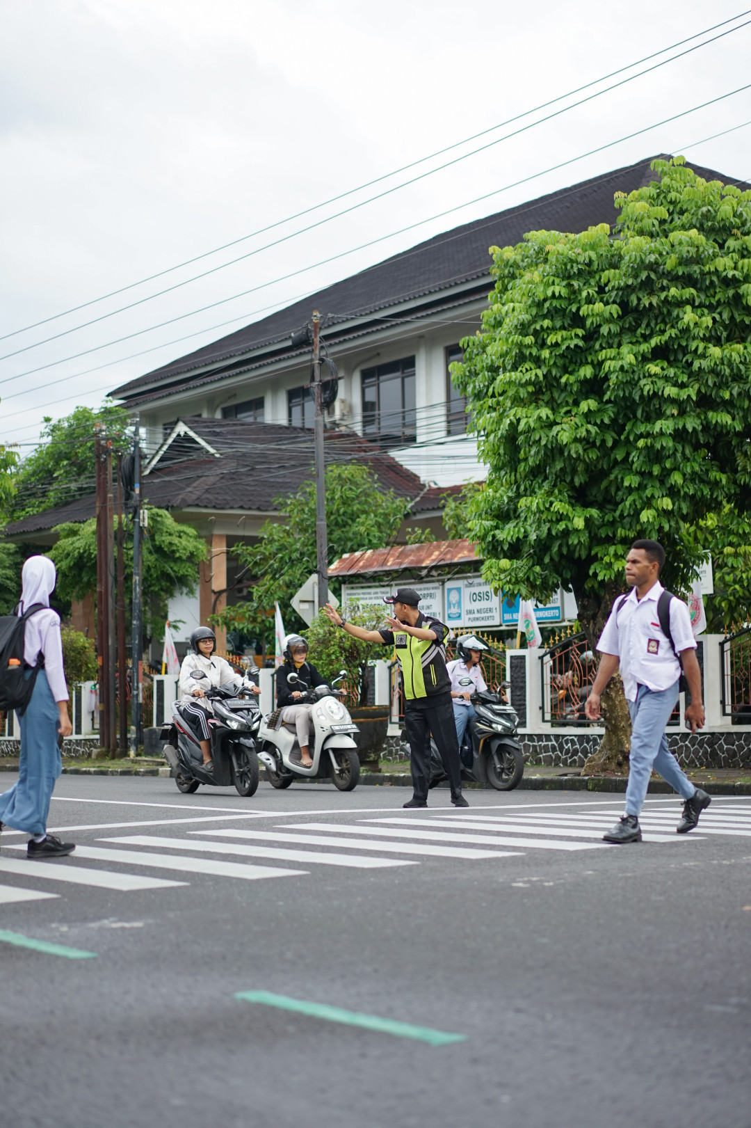 Satu kesatuan dalam satu lingkungan tengah terjadi antara pelajar, petugas keamanan, dan masyarakat awam. Ketiganya saling berinteraksi dalam ketertiban, menjunjung kesopanan dan kemurahatian. Sopan meminta untuk berhenti sejenak agar siswa-siswi dapat pergi bersekolah dan murah hati karena bersedia untuk berhenti sejenak dan memberi ruang.&nbsp;<br />
<br />
Dalam sela ketertiban itulah, kerukunan dan kebersamaan terjalin secara tidak langsung.