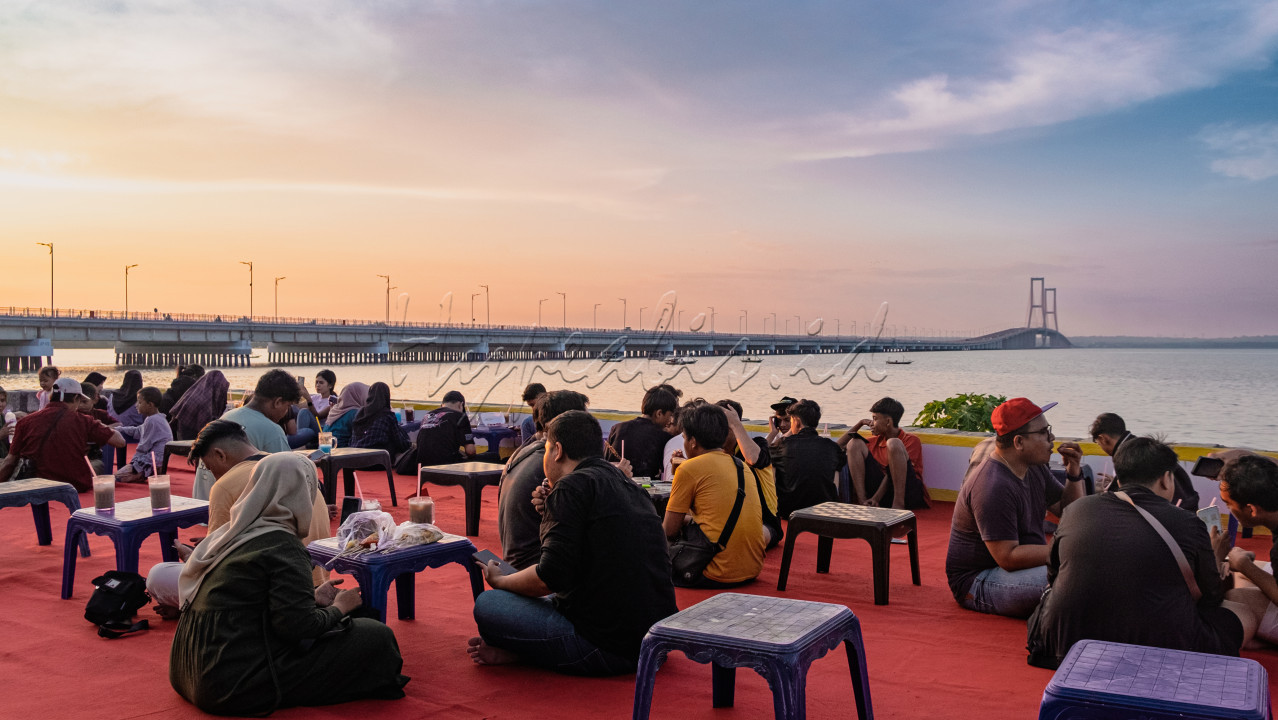 Masyarakat menikmati makanan dan minuman ringan dipinggir Jembatan Suramadu. Dengan adanya infrastruktur yang maju, maka akan berdampak juga pada pariwisata dan ekonomi di sekitar. Oleh karena itu pemerintah diharap terus melanjutkan pembangunan infrastruktur agar pariwisata dan ekonomi juga mengalami kemajuan.