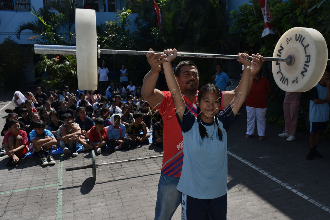 Seorang siswa SMP tersenyum saat Seorang atlet (berbaju merah) mengajarkan teknik dasar angkat besi kepada siswa di SMP Petra Malang, Jawa Timur. ( 15/8/2024). Ajang road show angkat besi tersebut ke beberapa sekolah. untuk mengenalkan dan meningkatkan minat cabang olah raga angkat besi sejak dini kepada siswa di daerah lebih mengenal sepak bola.&nbsp; Serta mencari atlet baru setelah Indonesia meraih medali emas angkat beban di Olimpiade Prancis 2024. <!--/data/user/0/com.samsung.android.app.notes/files/clipdata/clipdata_bodytext_241130_161244_496.sdocx--><br />
&nbsp;