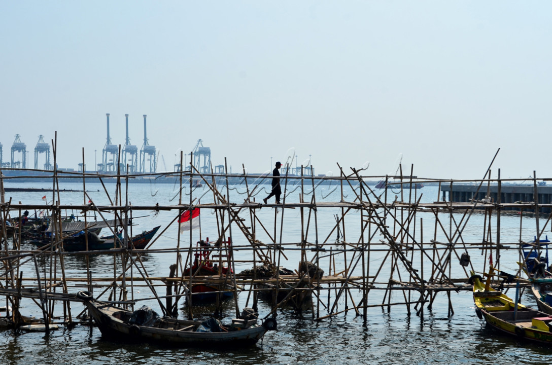 Sebuah imaji dari seorang pria yang terlihat tengah berjalan diatas jembatan bambu, yang dibuat oleh warga sekitar untuk menghubungkan daerah pemukiman penduduk dengan tanggul laut di kawasan pesisir Cilincing, Jakarta Utara.