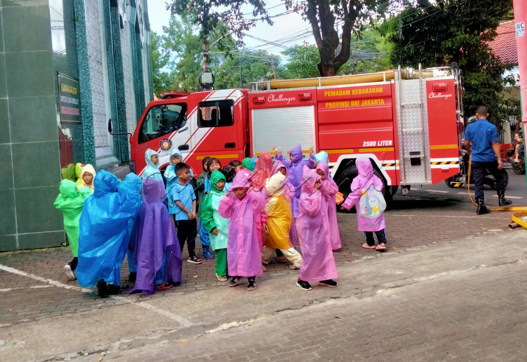 Terlihat anak-anak menggunakan jas ujan saat sedang panas, tetapi bukan menunggu hujan melainkan dia ingin bermain air