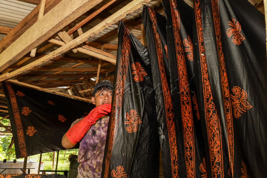 Hasil gambar yang melihat kan pemuda menjemur batik yang sudah di basuh untuk menghilangkan malem/ lilin.
