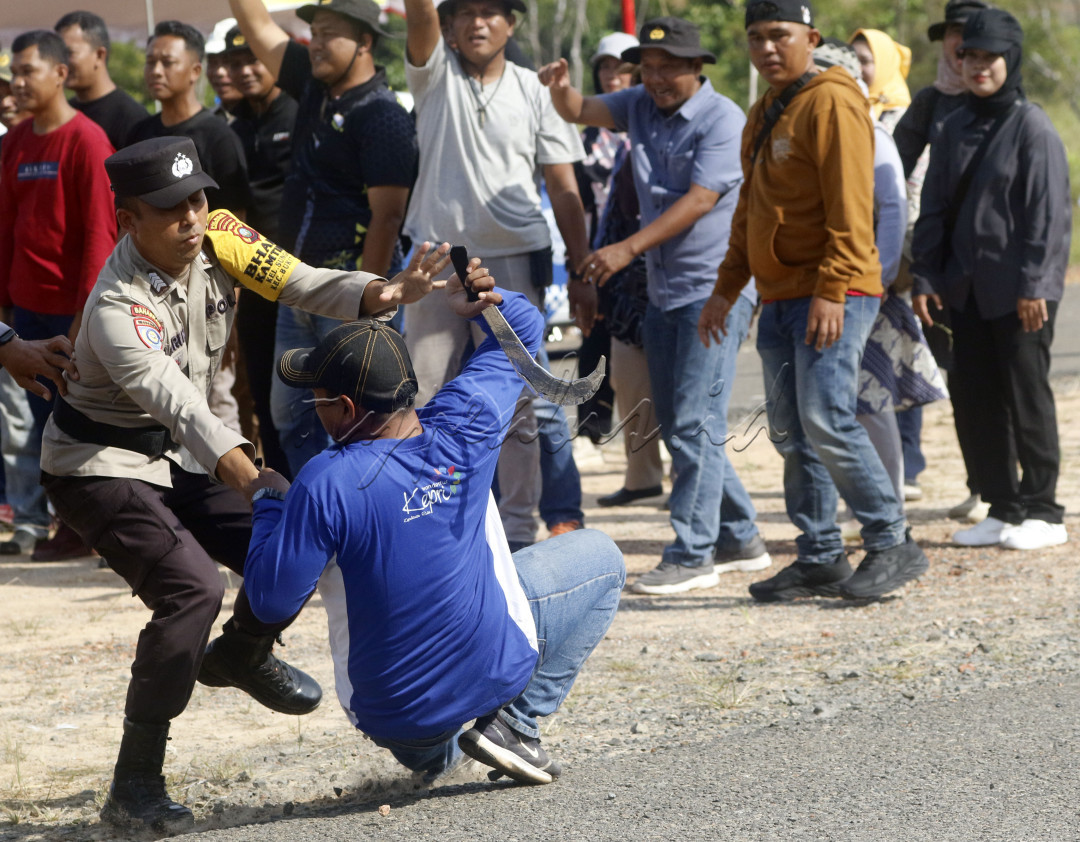 Seorang petugas polisi berusaha mengamankan seorang perusuh dengan membawa senjata tajam dalam simulasi pemilukada di Tanjungpinang, Kepri, 22 Agutus 2024.