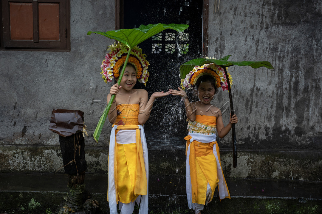 Dua anak kecil sedang bermain sembari menunggu hujan reda. Mereka adalah penari Rejang Pusung dari Desa Geriana Kauh, Selat, Karangasem, Bali.&nbsp;Rejang Pusung adalah&nbsp;tarian sakral yang berasal dari Desa Pakraman Geriana Kauh, Kecamatan Selat, Kabupaten Karangasem.&nbsp;Tarian ini merupakan persembahan khusus untuk Prajuru Adat dan Pamangku.