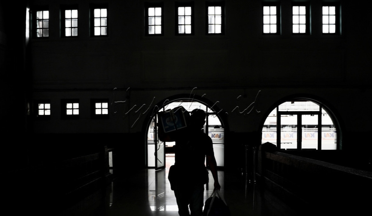 Siluet penumpang tiba di Stasiun Pasar Senen, Jakarta.