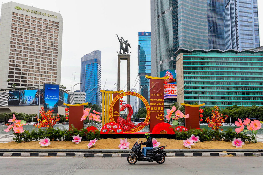 Pengendara sepeda motor melintasi dekorasi Tahun Baru Imlek di Bundaran HI, Jakarta, Senin (27/1/2025). Suku Dinas Pertamanan dan Kehutanan DKI menghiasi kawasan tersebut dengan ornamen bertemak Shio Ular Kayu untuk menyemarakkan Tahun Baru China 2576 Kongzili.