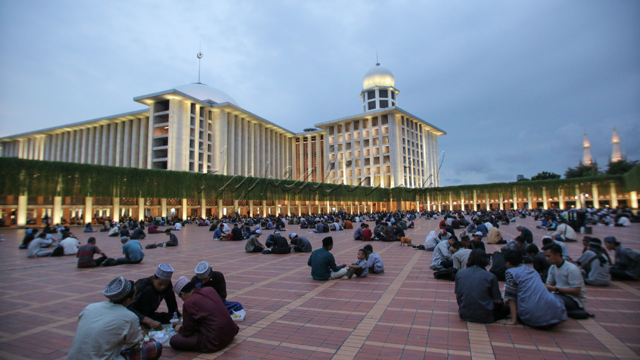 Warga berbuka puasa di area terbuka Masjid Istiqlal, Jakarta, Selasa (3/3/2025). Setiap hari masjid tersebut menyediakan 4.000 paket makanan gratis untuk berbuka puasa dan sahur.&nbsp;