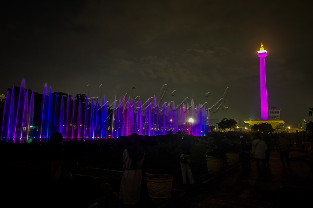 Sejumlah pengunjung menyaksikan pertunjukan air mancur menari di kawasan Monumen Nasional, Jakarta, Selasa (1/4/2025).