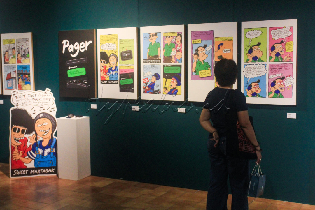 Pengunjung mengamati karya seni komik pada pameran tunggal Mice di Bentara Budaya, Jakarta, Kamis (15/5/2025). Pameran yang mengambil tema <em>Telekomunikasi Mengubah Peradaban</em> karya Mice ini bukan sekadar komik historis, tetapi refleksi eksistensial tentang bagaimana teknologi membentuk kehidupan manusia. Melalui satire visual, Mice mempertanyakan apakah kemajuan komunikasi benar-benar membuat manusia lebih beradab, atau justru menjauhkan kita dari kehadiran dan relasi yang otentik.