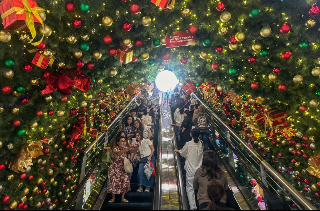 Pengunjung berswafoto di eskalator berdekorasi Natal di Pasific Place Mal, Jakarta.