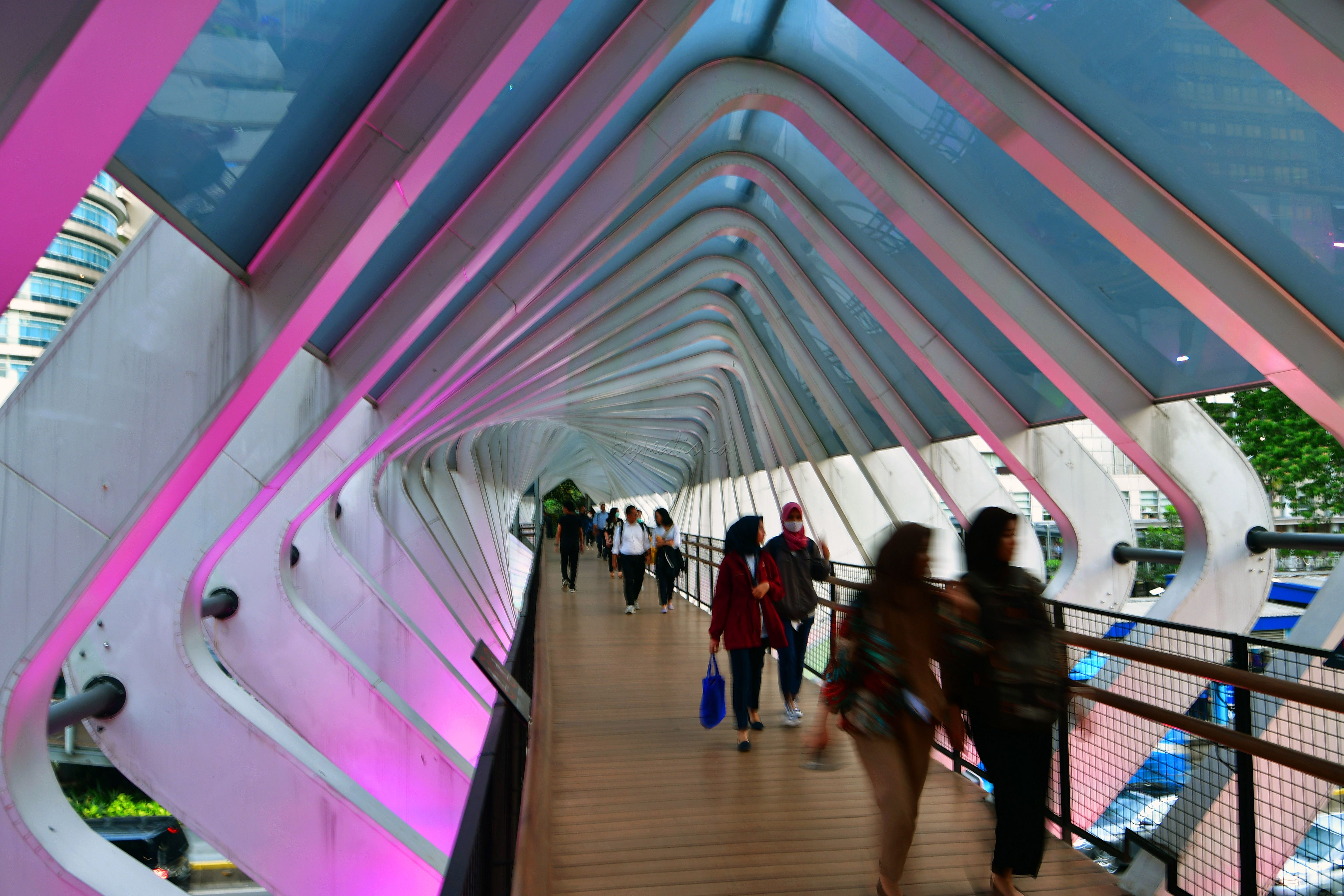 Warga melintas di jembatan penyeberang orang yang dibalut gemerlap aneka lampu.