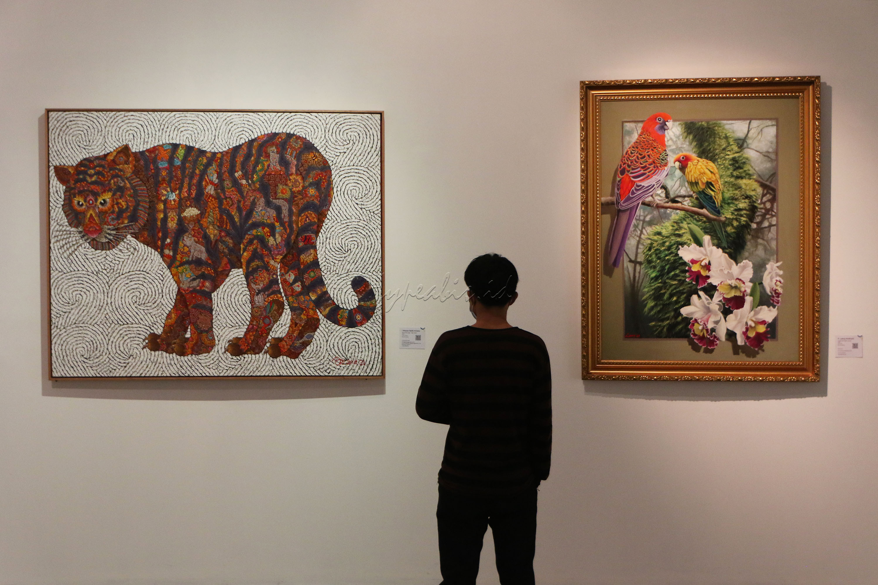 Pengunjung mengamati karya seni yang di pamerkan saat Pembukaan Art Moments Jakarta Online 2021 di Art:1 New Museum, Jakarta, Kamis (20/5/2021). Penyelenggara Art Moments Jakarta dengan bangga mengumumkan Art Moments Jakarta Online (AMJO) melalui platform virtual untuk pertama kali. Mulai tanggal 1 Juni hingga 30 Juni, pameran seni hybrid pertama di Indonesia ini dapat diakses melalui www.artmomentsjakarta.com, dan melalui aplikasi seluler Clamour. Art Moments Jakarta juga akan diadakan secara bersamaan yaitu tiga pameran offline di galeri seni ternama di Jakarta.
